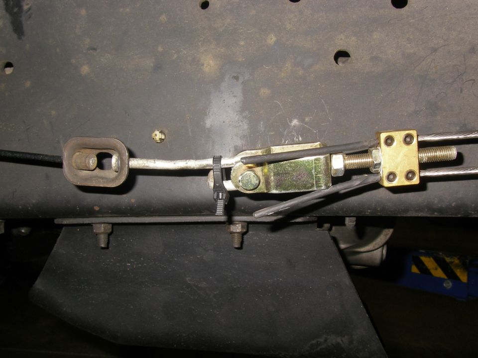 Parking brake cable equalizer clevis and yellow zinc adjuster under vehicle floor pan