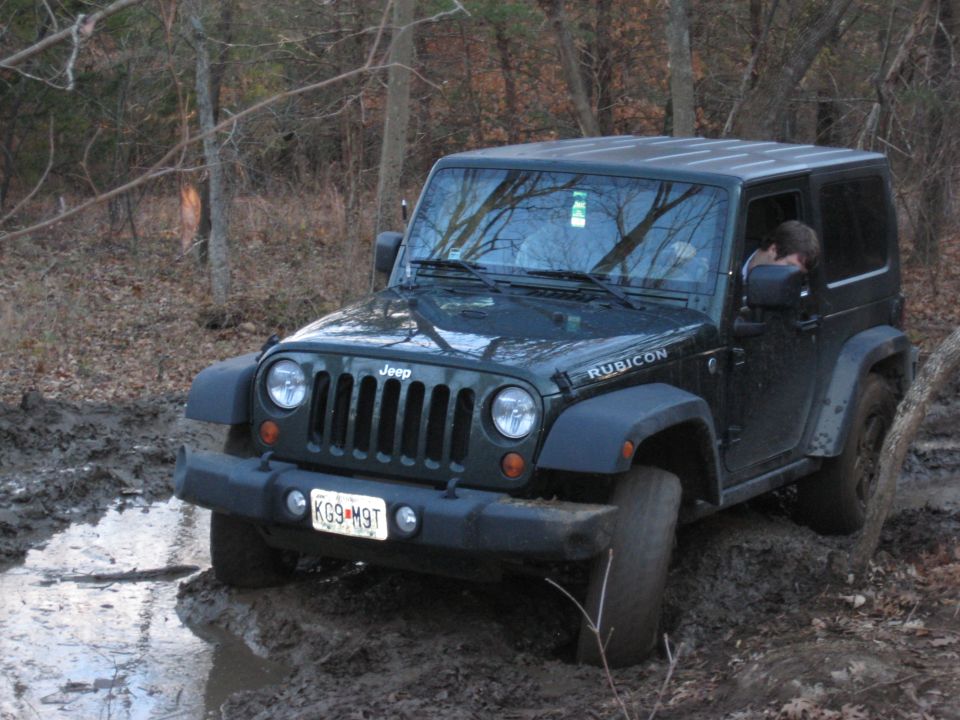 Dark green Jeep Wrangler Rubicon driving through mud. License plate KG9 M9T