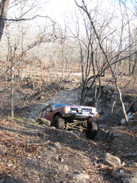 2005 Jeep Wrangler - A red Jeep Cherokee XJ tackles a challenging rocky trail during an off-road excursion.