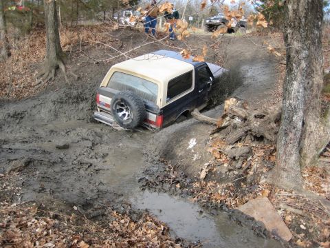 2005 Jeep Wrangler - A Ford Bronco navigates a muddy off-road course, with other vehicles visible in the background.