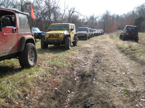 2005 Jeep Wrangler - A convoy of Jeep Wranglers drives down a dirt trail through a wooded area.