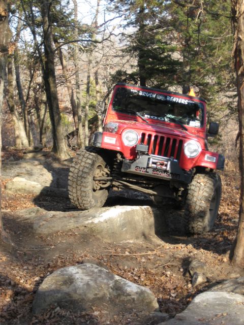 2005 Jeep Wrangler - This red 2005 Jeep Wrangler is shown tackling a challenging off-road course with large rocks.