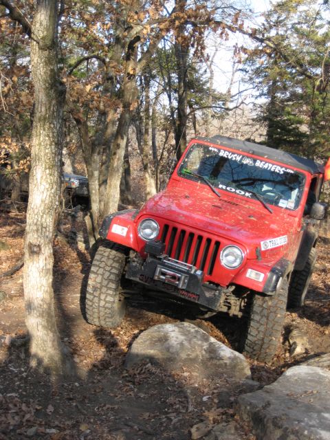 2005 Jeep Wrangler - 2005 Jeep Wrangler navigating a rocky off-road course with trees surrounding the path.