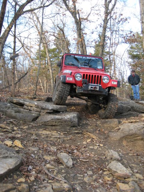 2005 Jeep Wrangler - A red Jeep Wrangler tackles a challenging rocky trail, demonstrating its off-road capabilities.