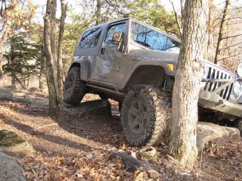 2005 Jeep Wrangler - A 2005 Jeep Wrangler Rubicon navigates a challenging rocky terrain on a wooded trail.