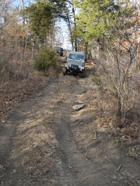 2005 Jeep Wrangler - A 2005 Jeep Wrangler navigates a rough, wooded trail with another Jeep visible in the background.