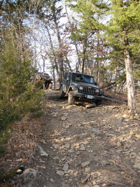 2005 Jeep Wrangler - Two Jeep Wranglers tackle a challenging, rocky trail in a wooded area.