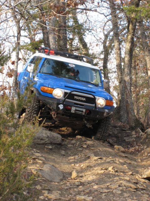 2005 Jeep Wrangler - A blue Toyota FJ Cruiser tackles a challenging rocky trail, demonstrating its off-road capabilities.