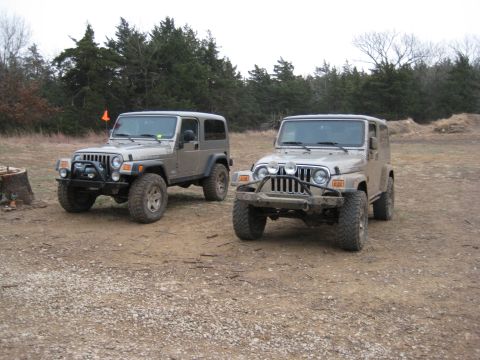 2005 Jeep Wrangler - Two Jeep Wranglers are parked in an outdoor lot with a wooded area behind them.