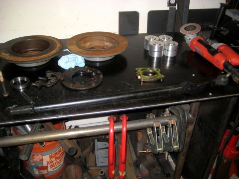 1996 Ford Bronco - Workbench with automotive parts including brake rotors, steering components, and tools.