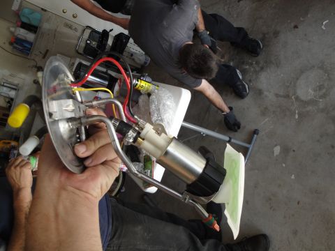 1995 Ford Taurus - A person holds a disassembled fuel pump assembly, showing the pump, filter, and associated wiring.