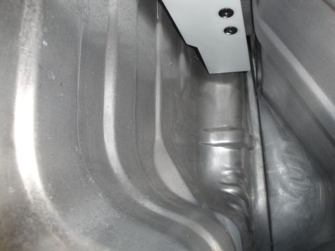 1995 Ford Taurus - The ribbed metal interior of a vehicle's trunk is visible, with a white bracket secured by two screws.