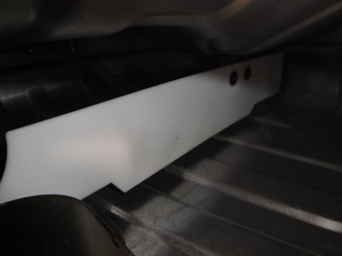 1995 Ford Taurus - White plastic underbody component with two circular holes, possibly a splash shield or trim piece.