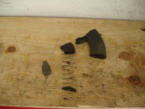 1989 Ford Bronco - The components of a firearm magazine are laid out on a wooden workbench.