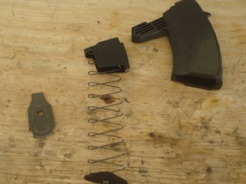 1989 Ford Bronco - A disassembled gun magazine lies on a wooden surface, showing its internal components.