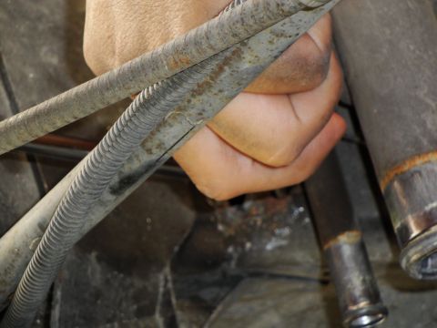 1995 Ford Taurus - A hand grips a bundle of corroded metal hoses, suggesting a mechanical repair or inspection.