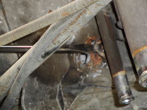 1995 Ford Taurus - The underside of a vehicle shows rusted pipes and connections, suggesting wear and tear.