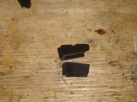 1989 Ford Bronco - Two black plastic automotive clips are shown on a wooden surface.