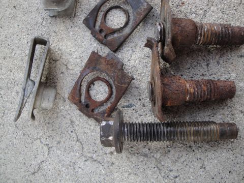1995 Ford Taurus - A collection of rusted bolts and metal clips are scattered on a concrete surface.
