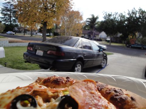 1995 Ford Taurus - Pizza in the foreground with a 1995 Ford Taurus parked on the street behind it.