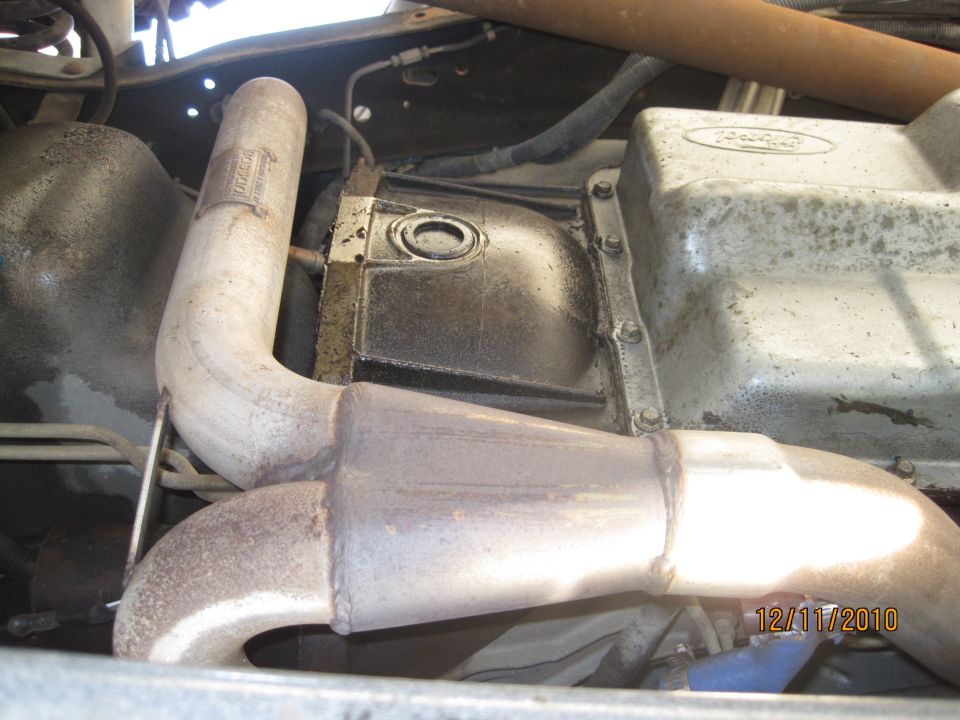 Exhaust pipe bends around a transmission pan with Ford logo