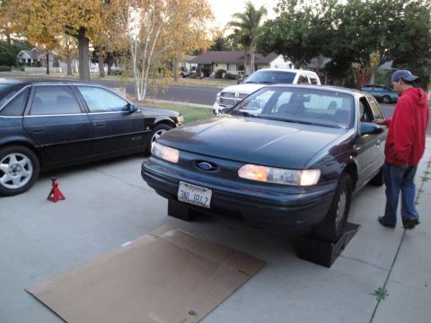 1995 Ford Taurus - 1995 Ford Taurus is being worked on, with other vehicles visible in the driveway.