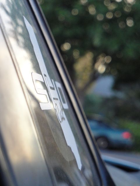 1995 Ford Taurus - A sticker is visible on a car window, with another vehicle blurred in the background.