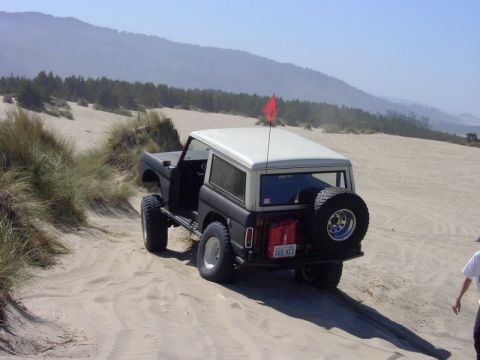 1980 Ford Bronco - This classic Ford Bronco is navigating a sandy terrain, kicking up dust as it goes.