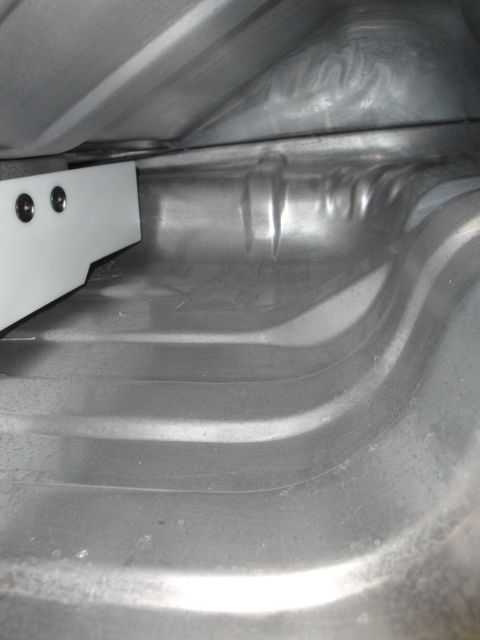 1995 Ford Taurus - The interior of a car's trunk is visible, showing the metal floor and a white bracket with two screws on the left side.