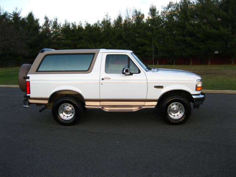 White 1996 Ford Bronco side view with brown trim and spare tire