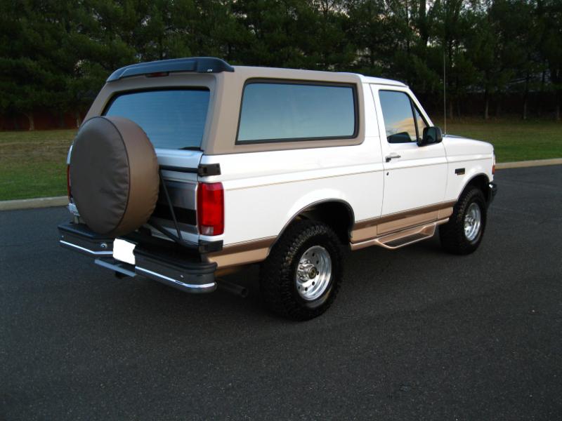 White 1996 Ford Bronco with tan top and spare tire on rear door