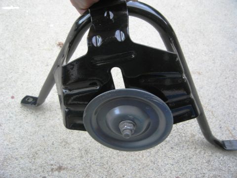 1986 Ford Bronco - A black metal tire carrier bracket is held up, showing its construction and a small wheel.