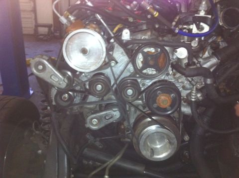 2008 Ford F-250 - Close-up of the front of a diesel engine with the fan shroud removed, showing the serpentine belt routed over the crank damper, water pump,…