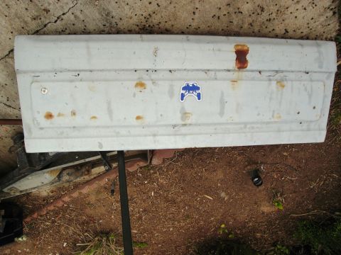 1986 Ford Bronco - This tailgate features a blue sticker of an off-road vehicle and shows signs of rust.