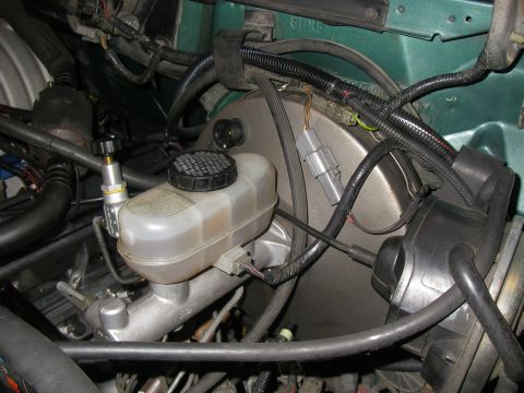 1990 Ford Bronco - Close-up view of the brake master cylinder and booster assembly in an engine bay.