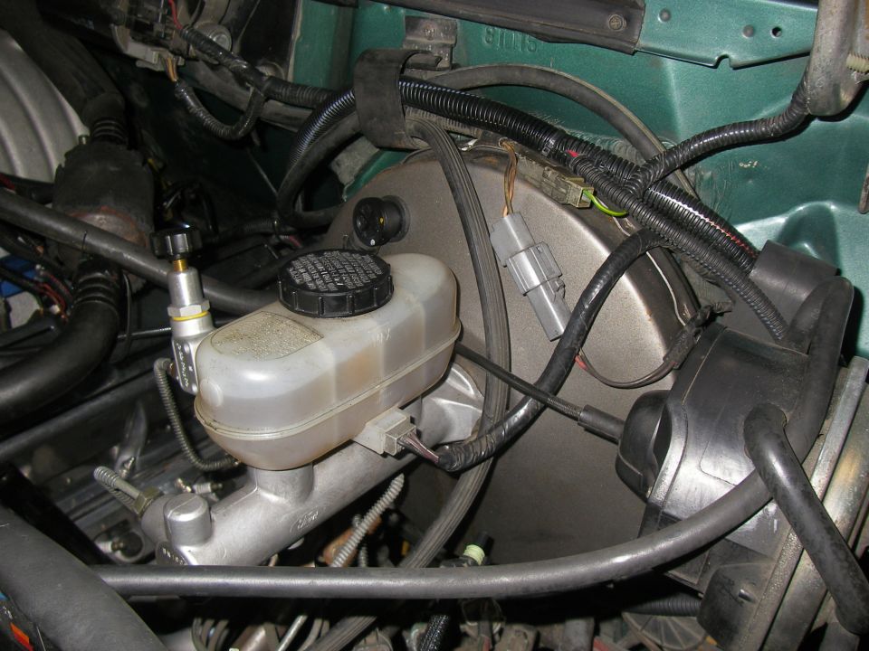 Brake master cylinder reservoir and booster assembly with various hoses and electrical connectors