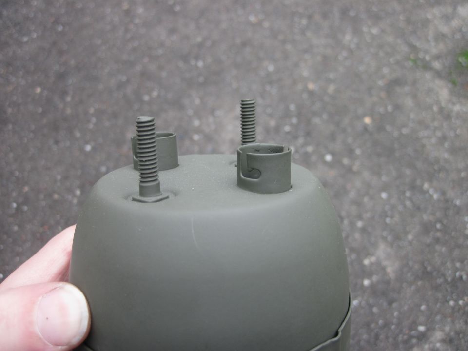 Gray painted gauge housing with three threaded posts and two mounting clips, held by a hand