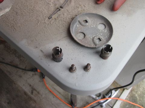 1979 Ford Bronco - Several metal automotive parts, including what appear to be sockets and bolts, are laid out on a dusty surface.