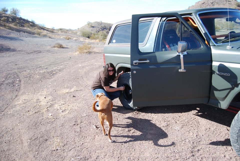 1982 Ford Bronco with door open, woman changing tire