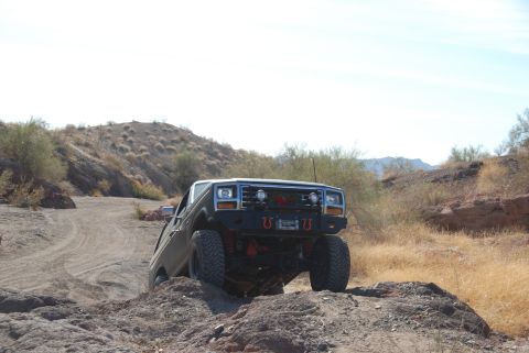 1982 Ford Bronco - A modified 1980s Ford Bronco navigates a challenging off-road course in a dry, arid landscape.