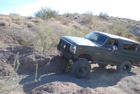 1982 Ford Bronco - Ford Bronco tackles a challenging off-road trail in a desert landscape.