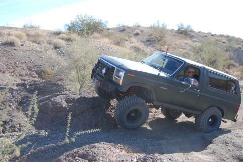 1982 Ford Bronco - A driver navigates a , desert terrain in a lifted Ford Bronco.