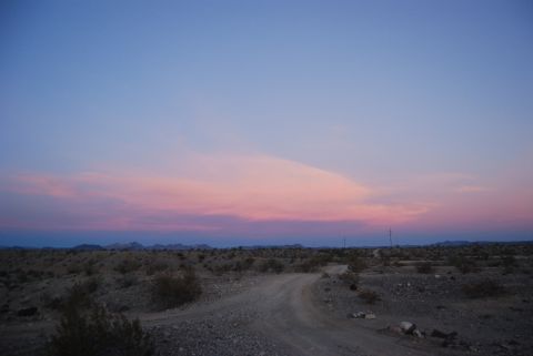 1982 Ford Bronco - A dirt road winds through a desert landscape under a colorful twilight sky.