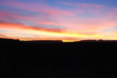 1982 Ford Bronco - Vibrant sunset paints the sky with hues of orange, pink, and blue over a dark, silhouetted desert landscape.