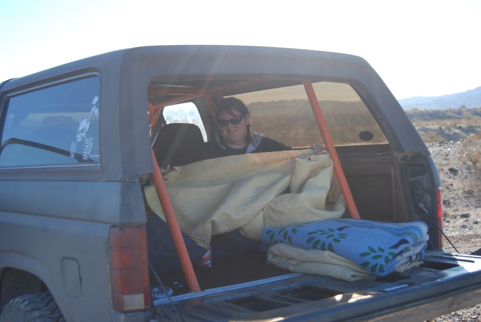 Interior of a Ford Bronco with a person and blankets, roll cage visible