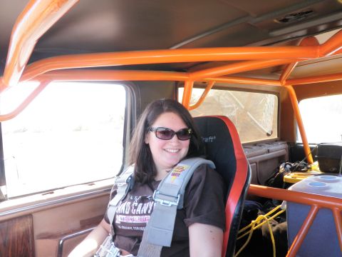 1982 Ford Bronco - A woman smiles from the driver's seat of a vehicle equipped with a roll cage and racing harness.