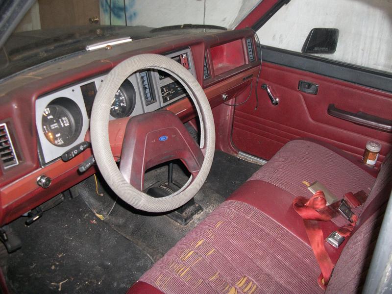 Interior of a 1987 Ford Ranger with red upholstery and a cracked dashboard