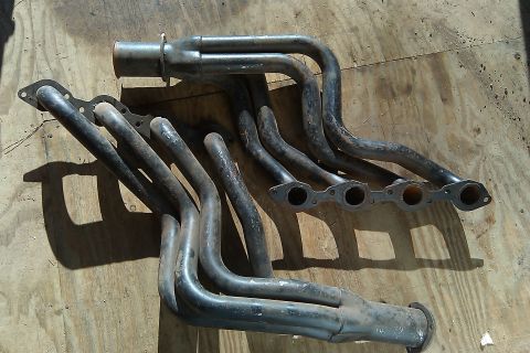 1987 Ford Bronco - These exhaust headers are for sale and appear to be used. They are made of metal and have a weathered appearance.