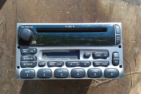 1987 Ford Bronco - A car stereo unit with a CD slot and tape deck is shown against a wooden background.