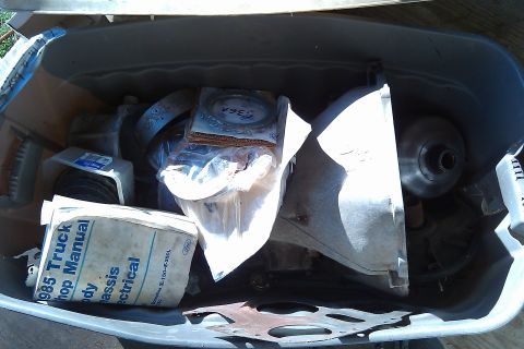 1987 Ford Bronco - Bin filled with various automotive parts and a 1985 Truck Shop Manual.